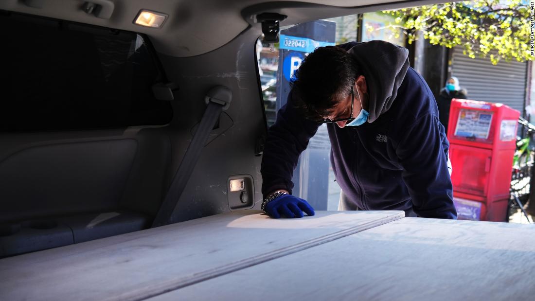 A man pauses as he places the casket of a relative into a van at a busy New York funeral home on May 9.