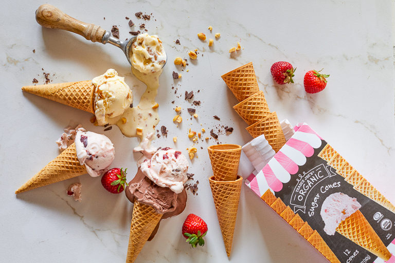 Trader Joe's Organic Sugar Cones laid on their sides with scoops of melted ice cream, next to product packaging